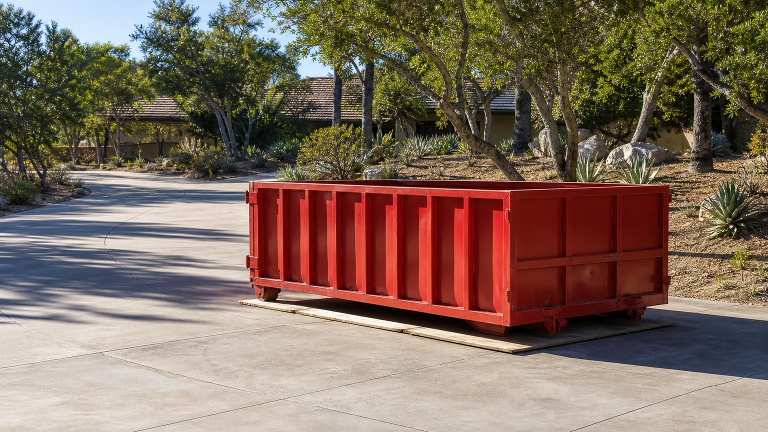 Red roll-off dumpster placed on a broad private driveway at a Bonita residence