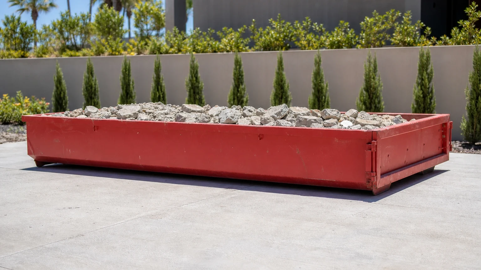 Long shallow red 10-yard lowboy loaded below the rim with clean broken concrete