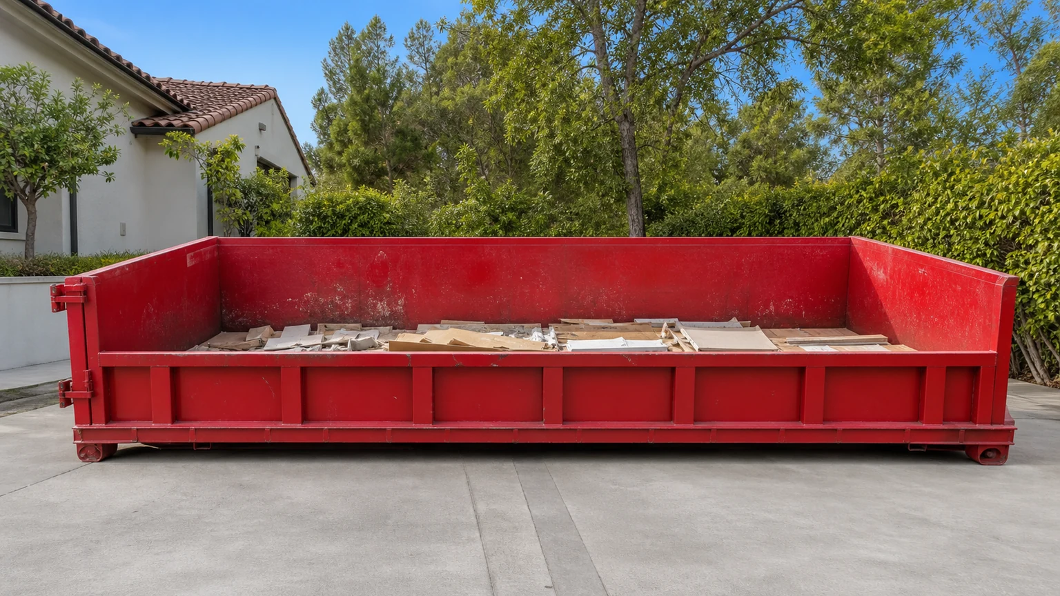 Red roll-off dumpster with a shallow organized layer of general debris well below the top rim