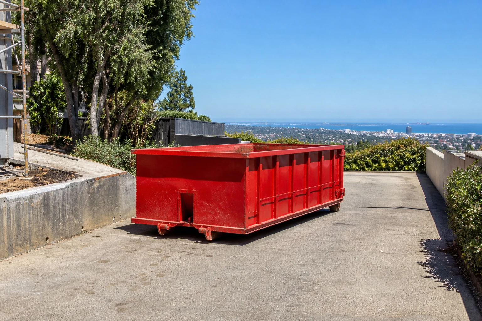 Red construction dumpster placed with clear paved jobsite access and open loading space