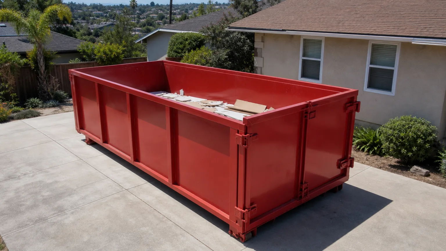 Plain red roll-off dumpster holding short remodel debris below the top rail
